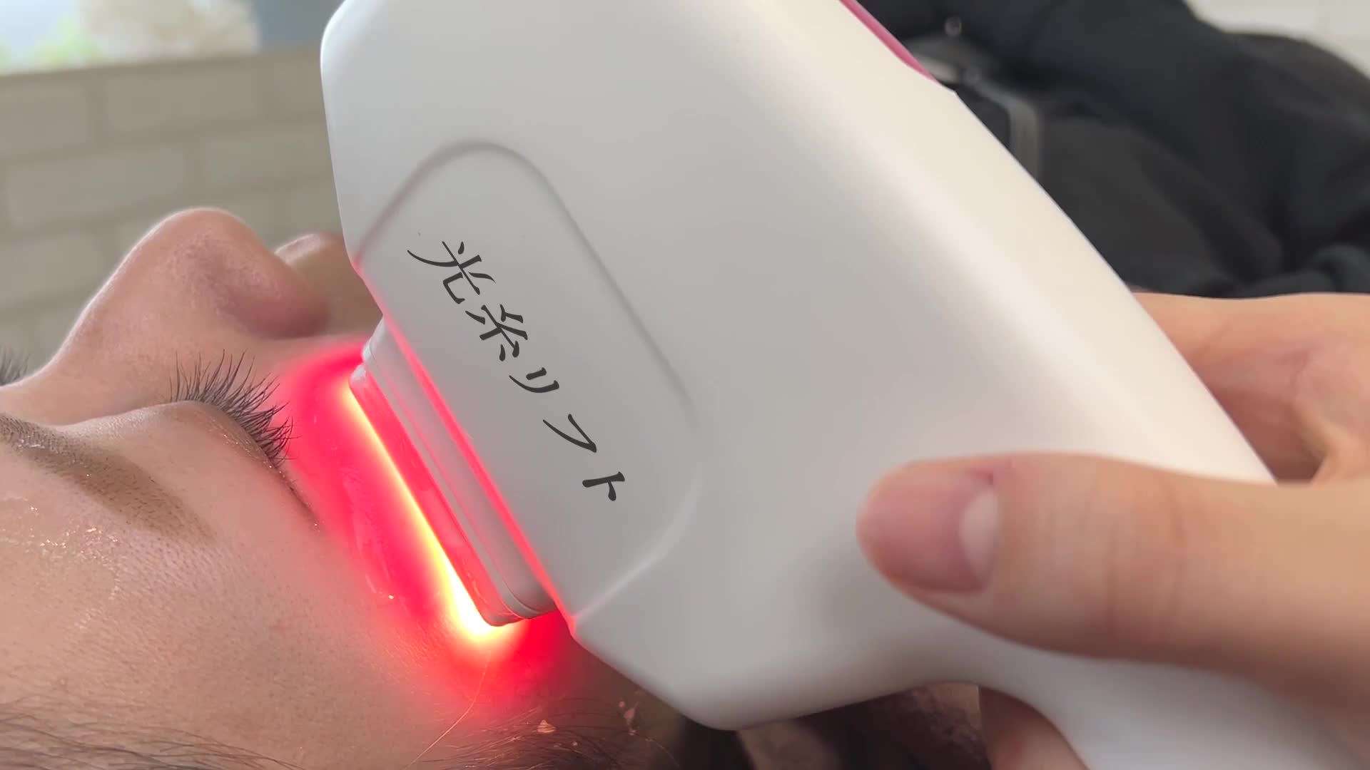 お客様の頬にハンドピースを当てるフェイシャル施術